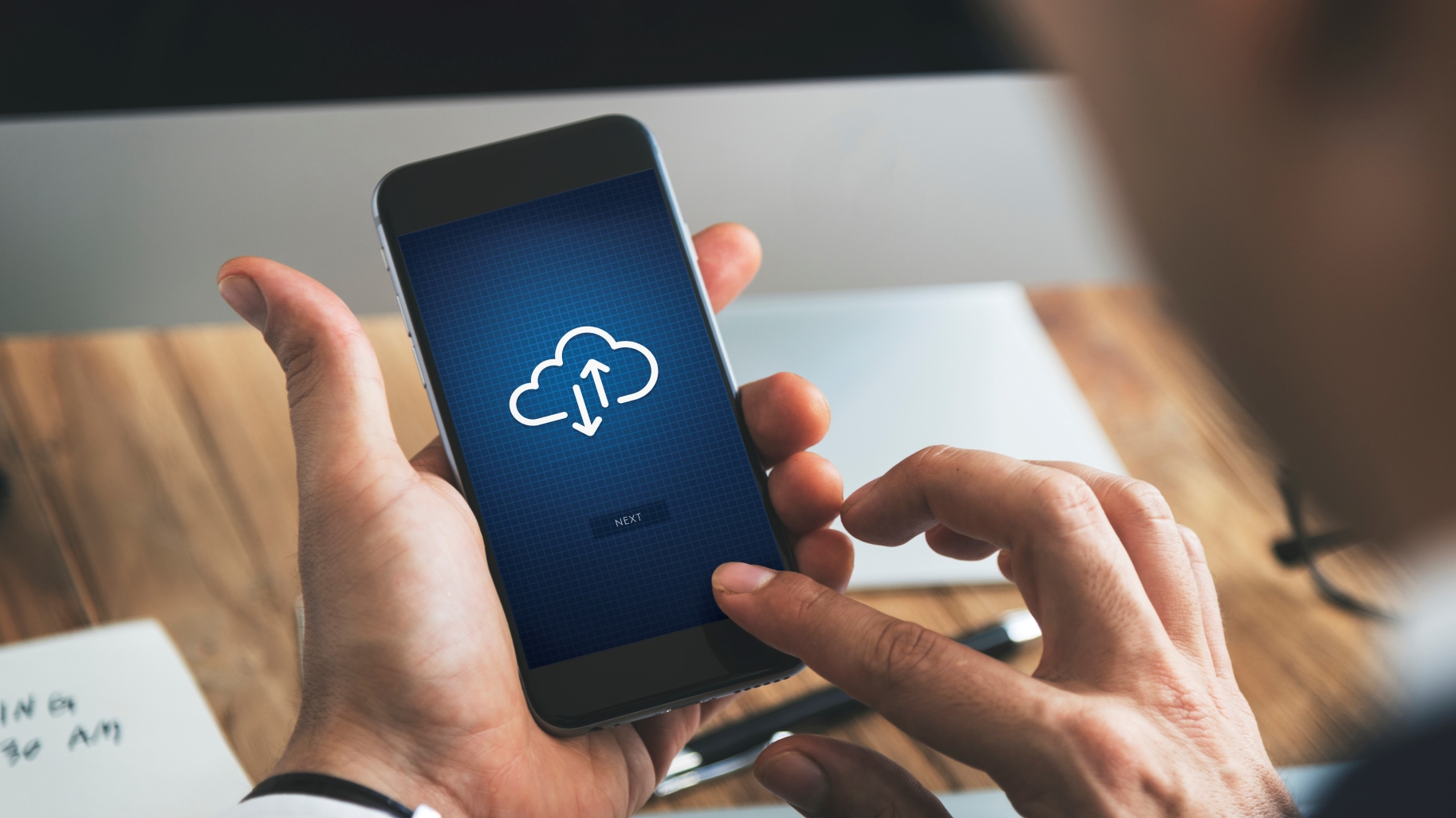 Personne tenant un smartphone affichant le symbole du  cloud computing (informatique en nuage)