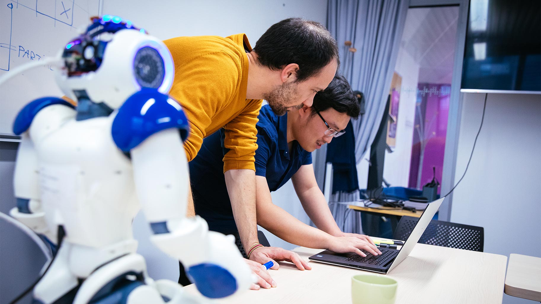 Deux personnes devant un ordinateur portable avec un robot