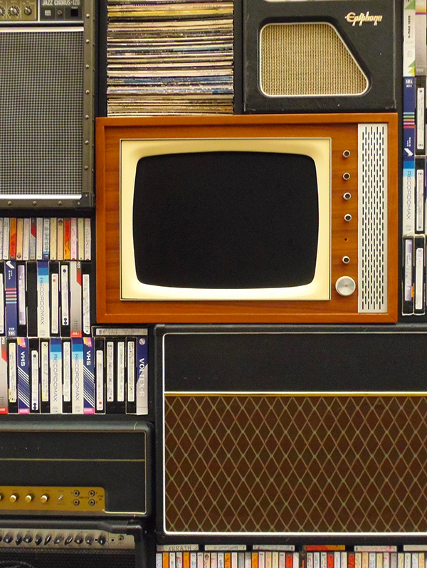 vieux poste de télévision encadré par des vinyles et des cassettes VHS