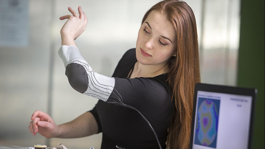 Femme qui travaille sur un haut remplit de capteurs pour collecter des données sur les interactions physiques